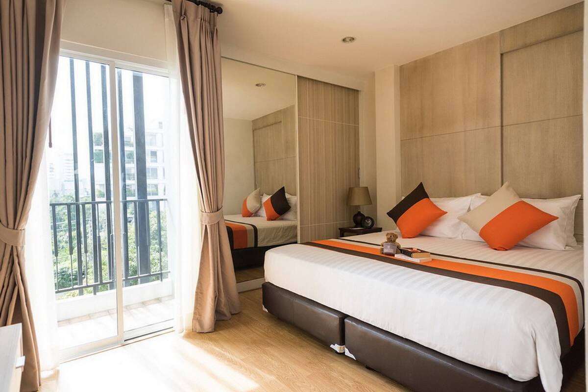 Een moderne hotelkamer met een groot bed, een balkon en uitzicht op de stad.