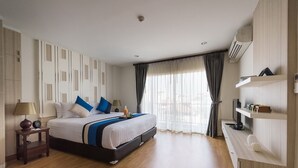 Une chambre d’hôtel avec un grand lit, une table de chevet avec une lampe, une télévision et une étagère contenant des articles de toilette.