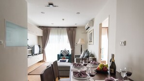 Un espace de repas moderne avec une table dressée pour quatre personnes, un canapé en arrière-plan et une vue sur le salon.