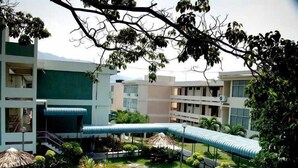 A courtyard with a central water feature, surrounded by greenery and modern buildings with balconies. - International House (George Town)