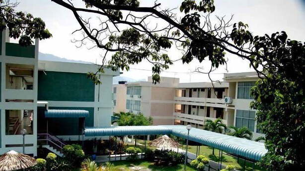 A courtyard with a central water feature, surrounded by greenery and modern buildings with balconies. - International House (George Town)