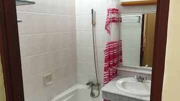 Ein Badezimmer mit einer weißen Badewanne, einer Dusche, einem Waschbecken und einem Spiegel.