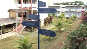 A signpost with directions to various building blocks and amenities such as a gymnasium, swimming pool, and cafeteria. - International House (George Town)