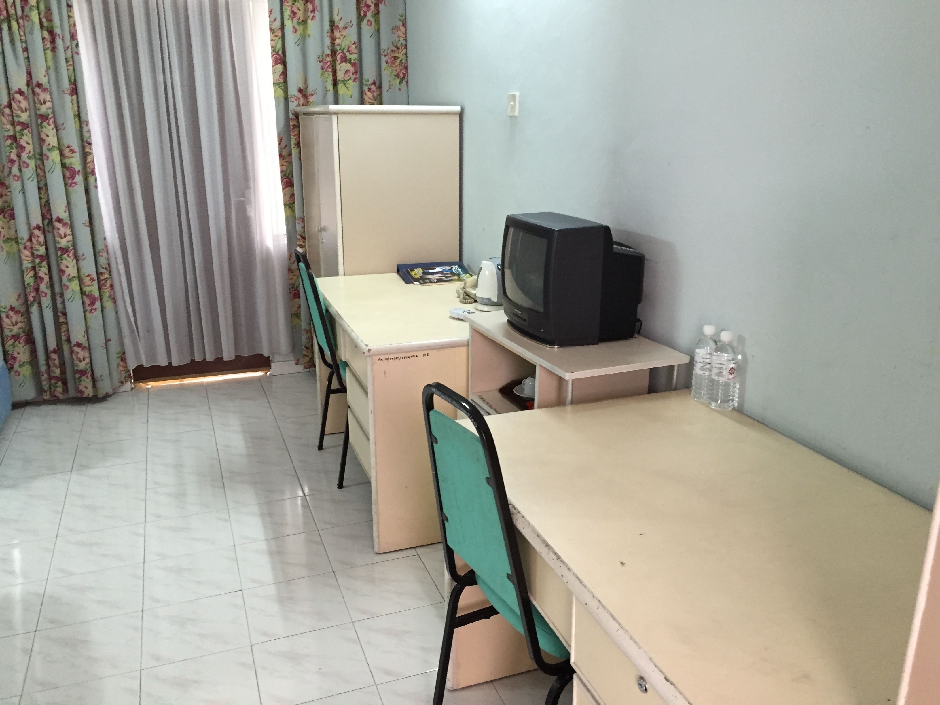 Una habitación pequeña y sencilla con escritorio, silla y televisión.