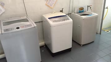 A laundry area with three washing machines, a water heater, and a water meter.