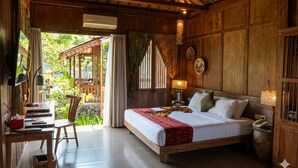 A wooden room with a bed, a desk, and a chair. - Amata Borobudur Resort (Mungkid)