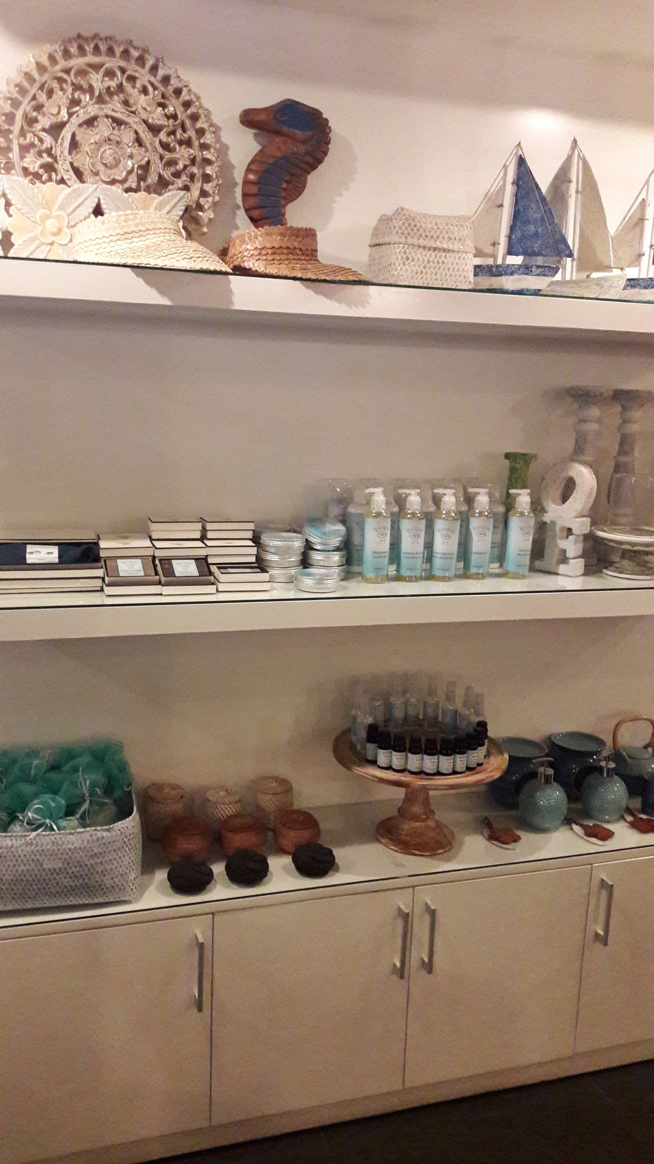 A shelf with decorative items, including a seahorse, a sailboat, and various bottles.