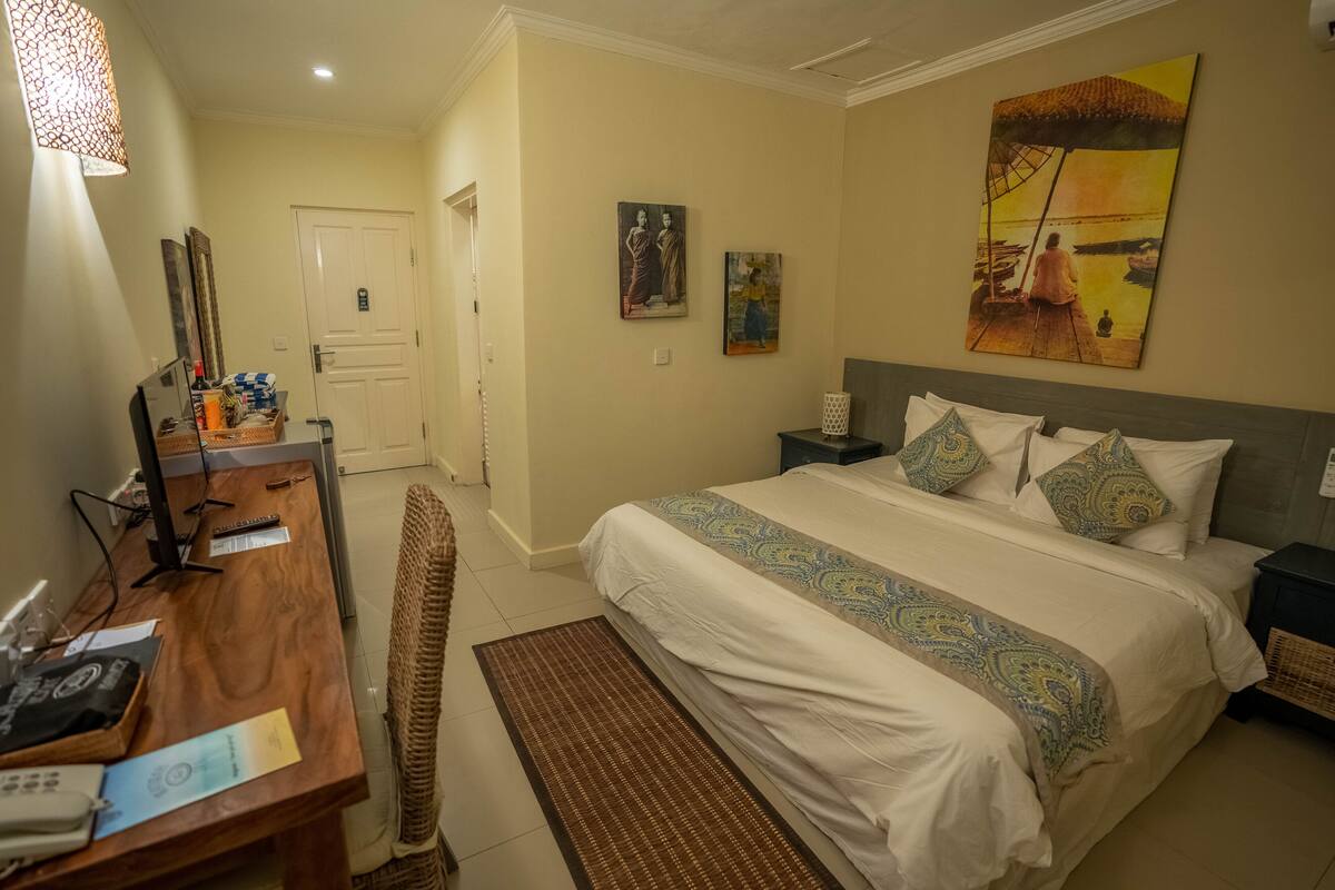 Une chambre d’hôtel avec un lit, un bureau, une chaise et des œuvres d’art accrochées aux murs.