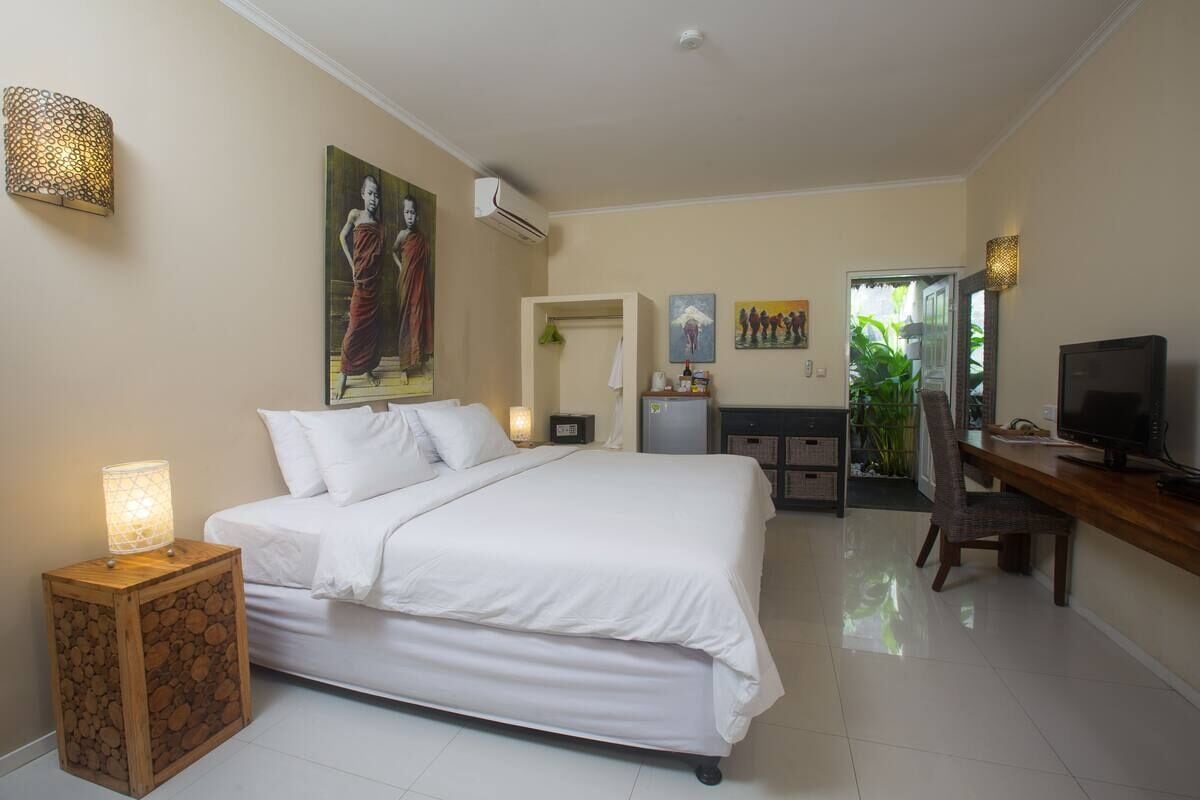 Un dormitorio con cama, mesita de noche, lámpara, obra de arte, escritorio, silla, televisor y vistas al exterior.
