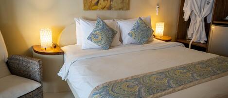 A hotel room with a large bed, two bedside lamps, a chair, and a robe rack.