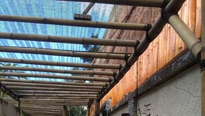A covered walkway with a stone floor, bamboo ceiling, and walls lined with potted plants. - Scallywags Resort (Gili Trawangan)
