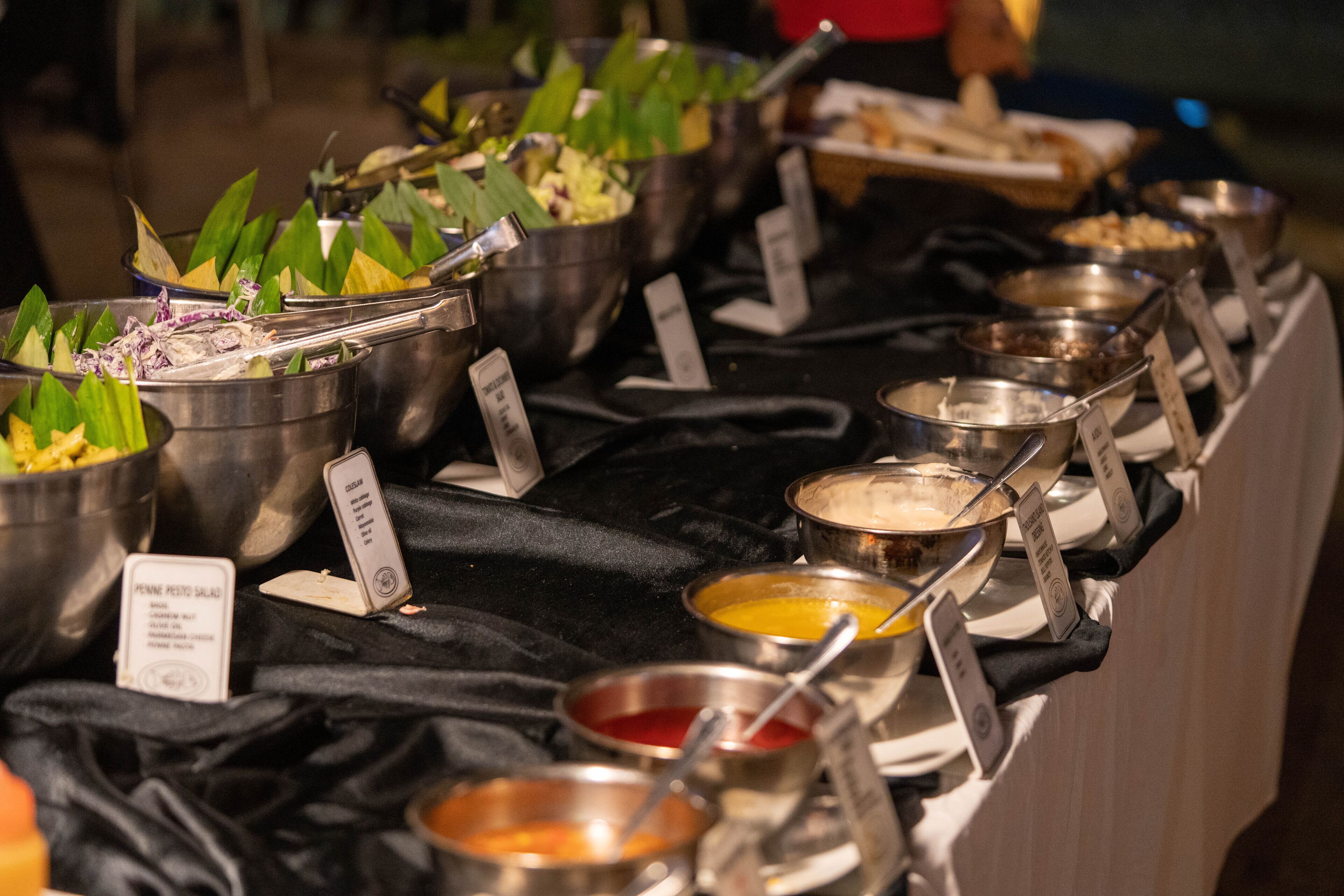 Une table de buffet avec divers plats et des récipients contenant des condiments.