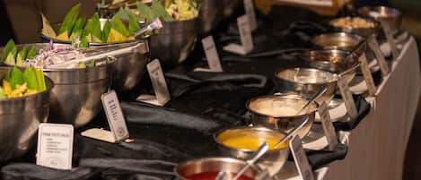 A buffet table with various food items and condiment containers.