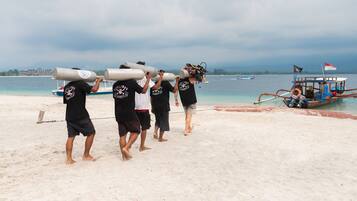 A group of people carrying large cylindrical objects on their shoulders on a beach.