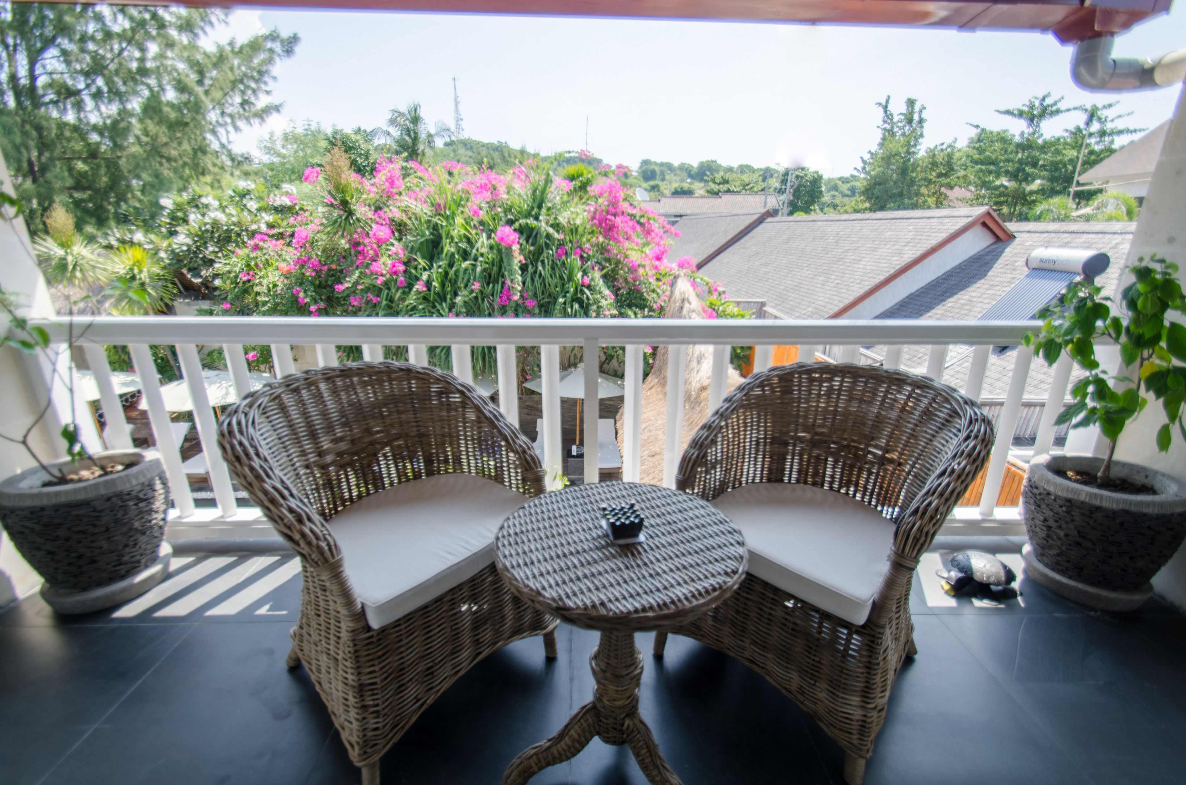 A balcony with wicker furniture and potted plants.