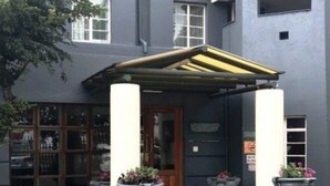 Un bâtiment doté d’une entrée abritée, de grandes fenêtres et de plantes en pot.