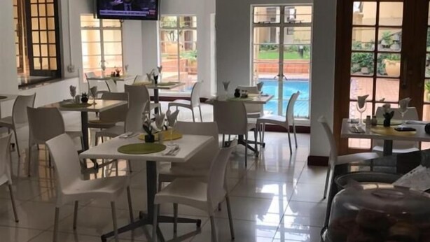 Un espace repas avec des tables et des chaises, un téléviseur fixé au mur et une vue sur une piscine.