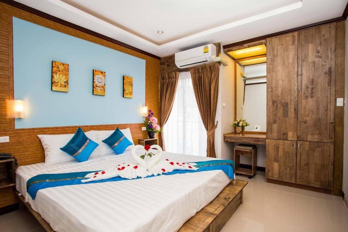 A hotel room with a large bed, wooden headboard, and a wardrobe.