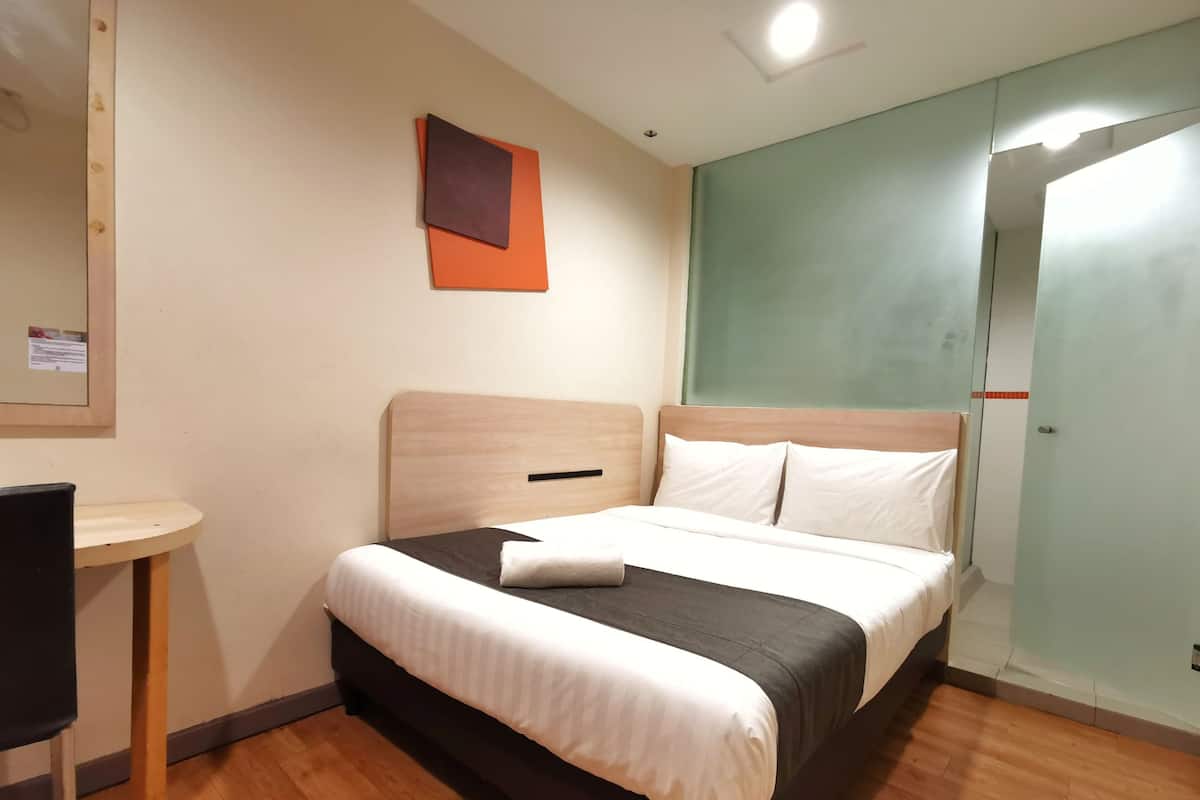 Ein Hotelzimmer mit Bett, einem kleinen Tisch und einem Spiegel.