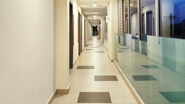 A long, well-lit corridor with a tiled floor, glass partitions, and doors on one side. - Hotel 98 (Kuching)
