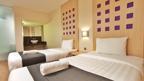 A hotel room with two beds, a bathroom with a sink, and a mirror. - Hotel 98 (Kuching)