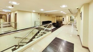 A modern hotel lobby with a glass staircase, a reception desk, and a seating area. - Hotel 98 (Kuching)