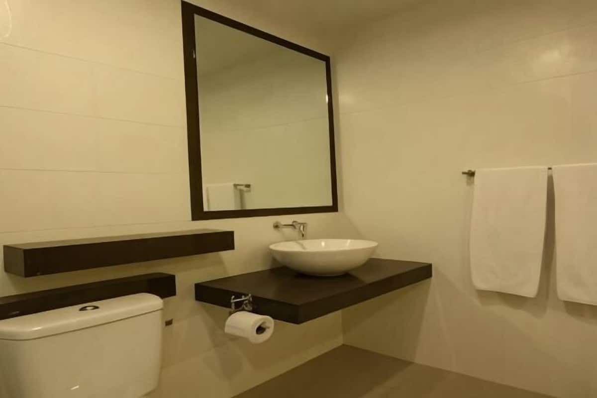 Ein Badezimmer mit Toilette, Waschbecken mit Spiegel darüber und Handtuchhalter mit zwei Handtüchern.