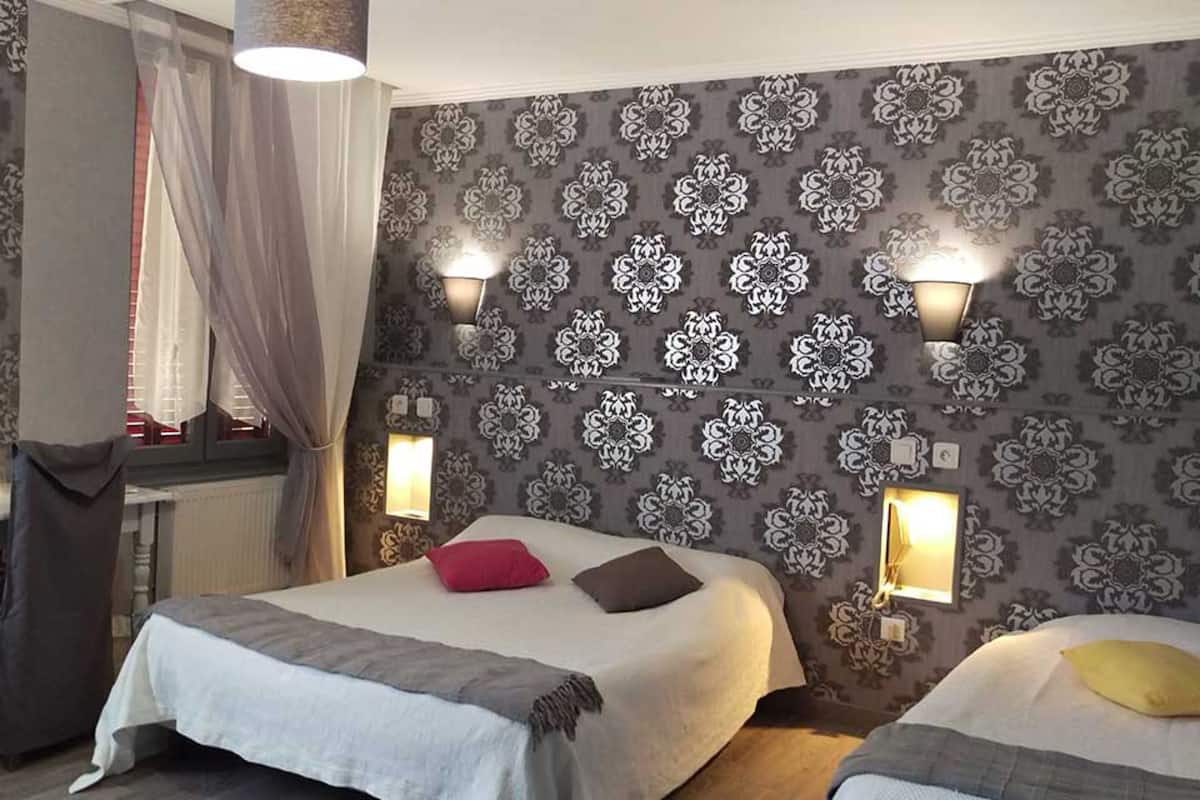 A hotel room with two beds, patterned wallpaper, and wall-mounted lamps.