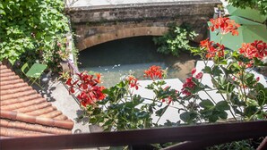 Vista de uma ponte sobre um curso d'água, com flores vermelhas em primeiro plano.