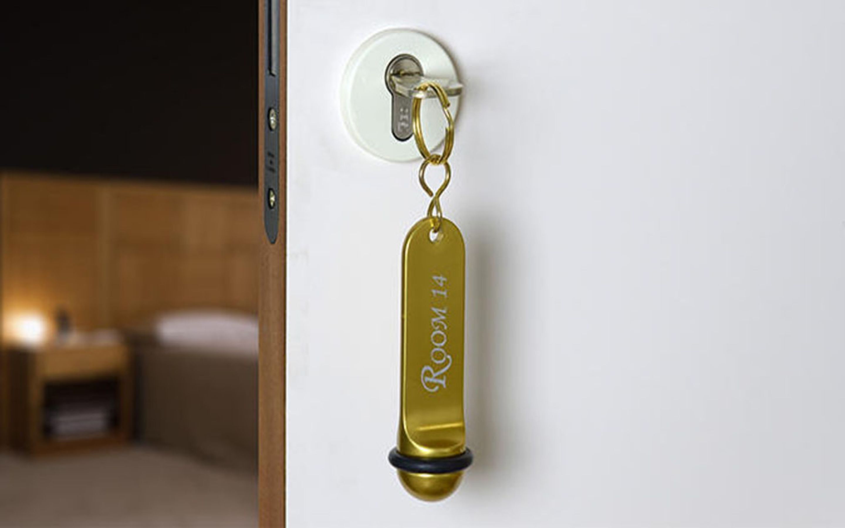 Un porte-clés avec la mention « Chambre 14 » gravée dessus, accroché à la poignée d’une porte.