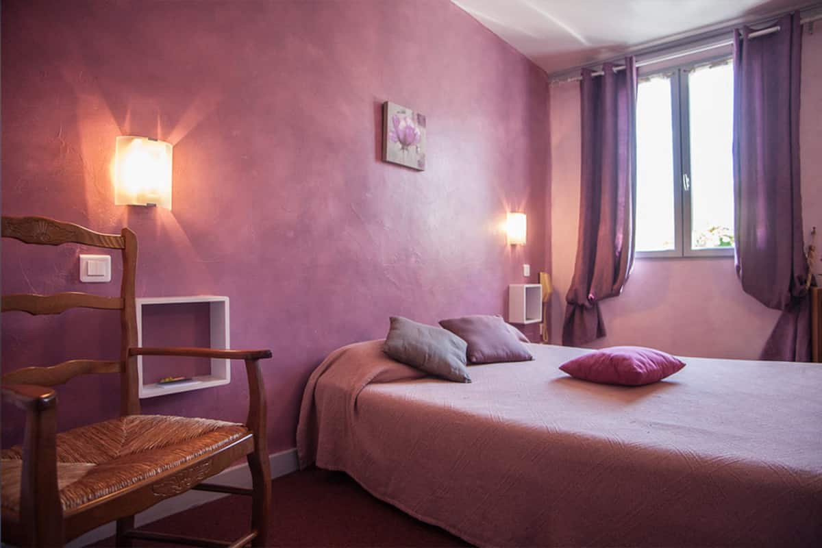 A bedroom with a bed, a chair, and two wall-mounted lights.