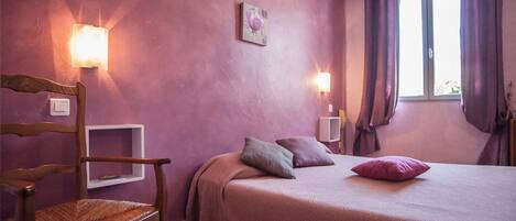 Un dormitorio con una cama, una silla y dos luces en la pared.