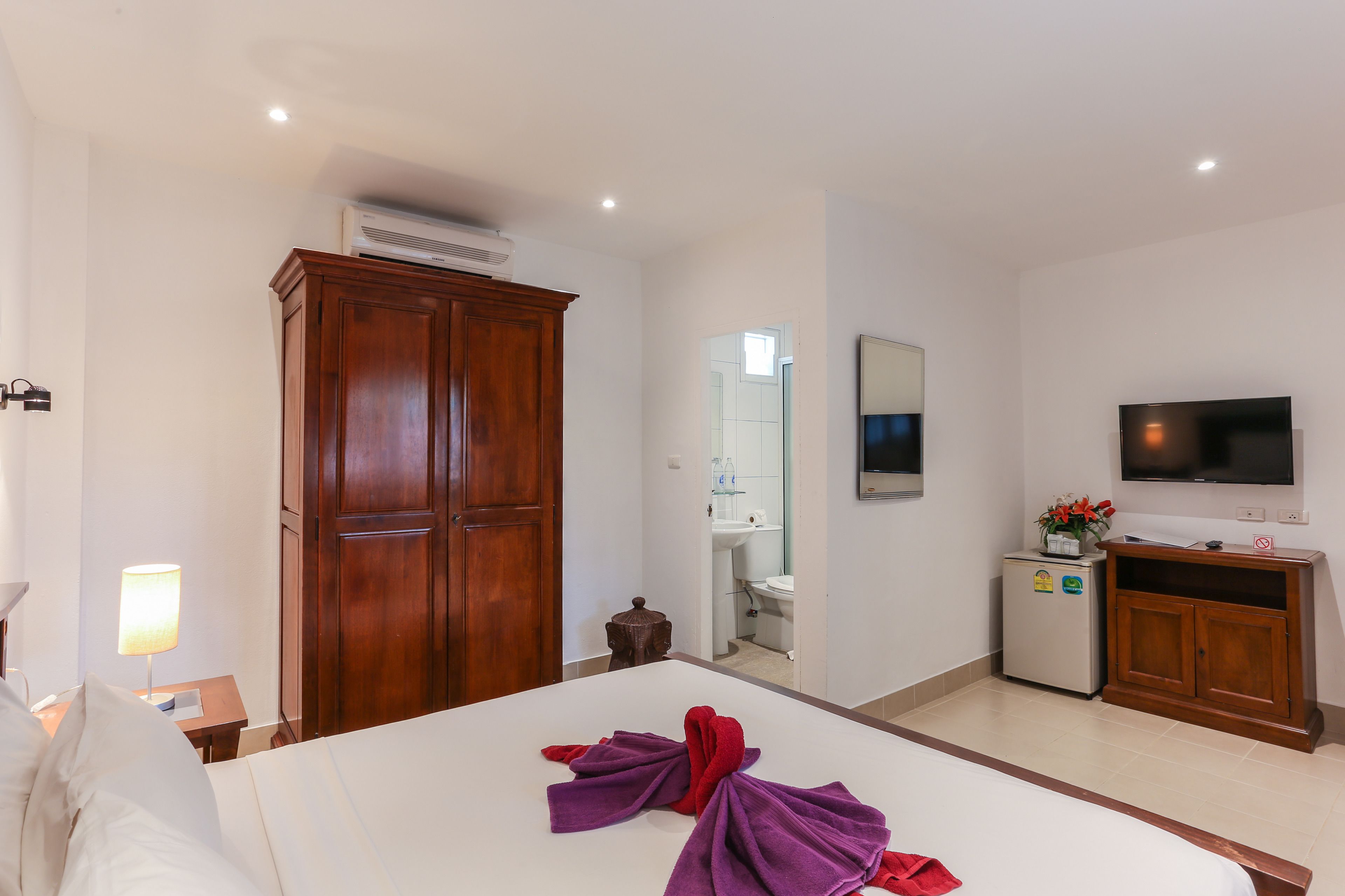 Une chambre d’hôtel avec un grand lit, une armoire, une télévision et une petite kitchenette.