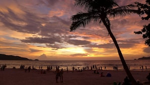 Ein Strand mit Menschen und Palmen bei Sonnenuntergang.