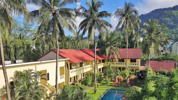Ein Resort mit Swimmingpool, umgeben von Palmen und einem Bergpanorama.