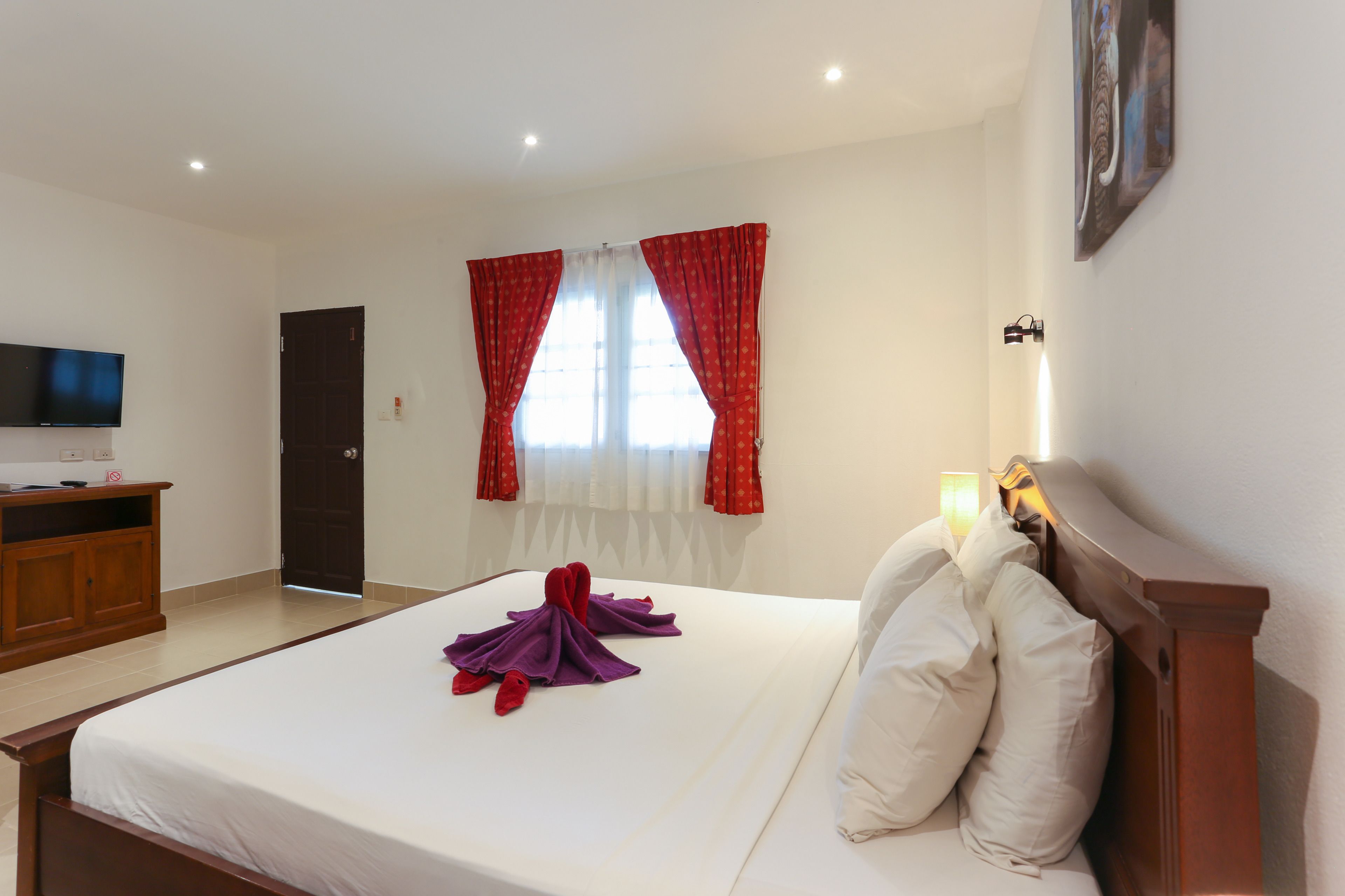 Une chambre d’hôtel avec un lit, une télévision, une armoire et une porte.