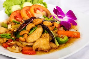 A plate of stir-fried chicken with vegetables and cashews.