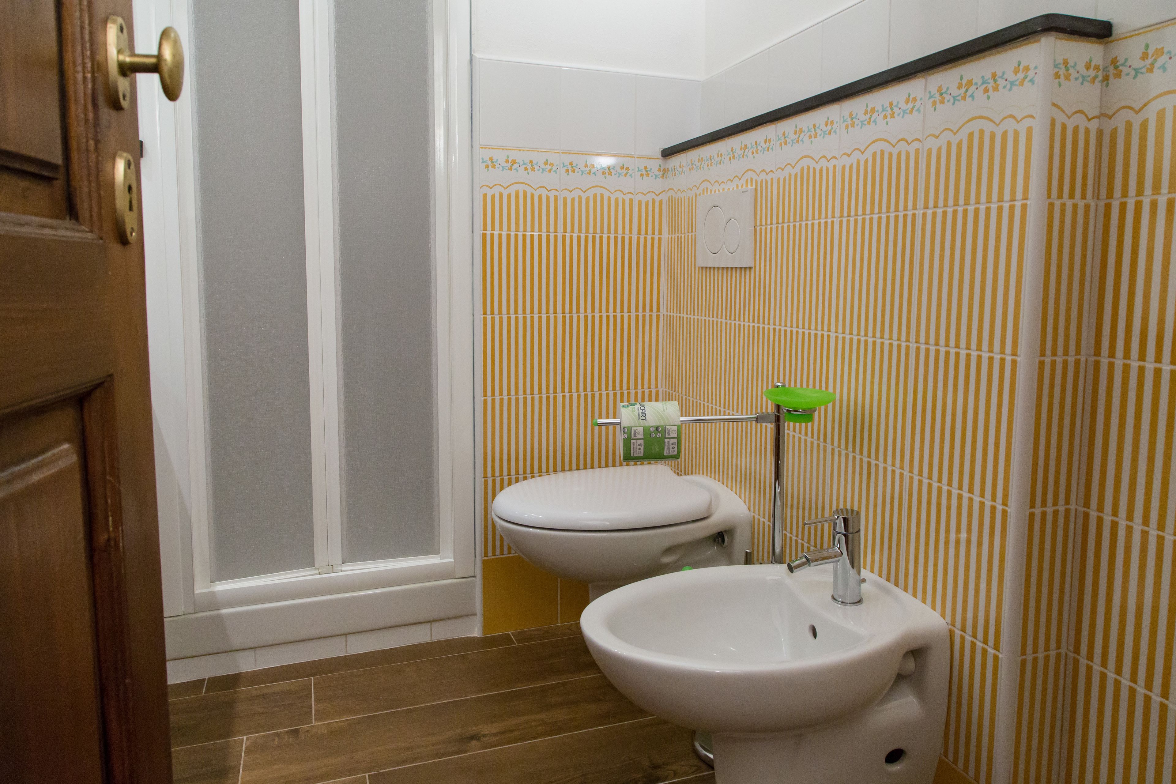 Une salle de bain avec une porte en bois, des toilettes, un bidet et un lavabo.