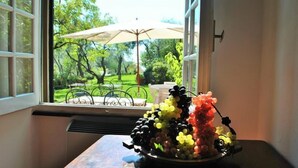 Une fenêtre donnant sur un jardin et sur du mobilier d’extérieur.
