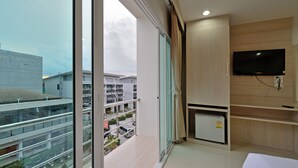 A modern hotel room with a large window, a flat-screen TV, and a small refrigerator. - Baan Kure Ngern Aonang (Krabi)