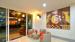 A lobby with wicker furniture, a large wall mural, and a glass door leading to the street. - Baan Kure Ngern Aonang (Krabi)