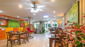 A hotel lobby with a reception desk, seating area, ceiling fans, and decorative plants. - Baan Kure Ngern Aonang (Krabi)