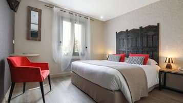 A bedroom with a bed, a red chair, a nightstand, and a wall-mounted mirror.