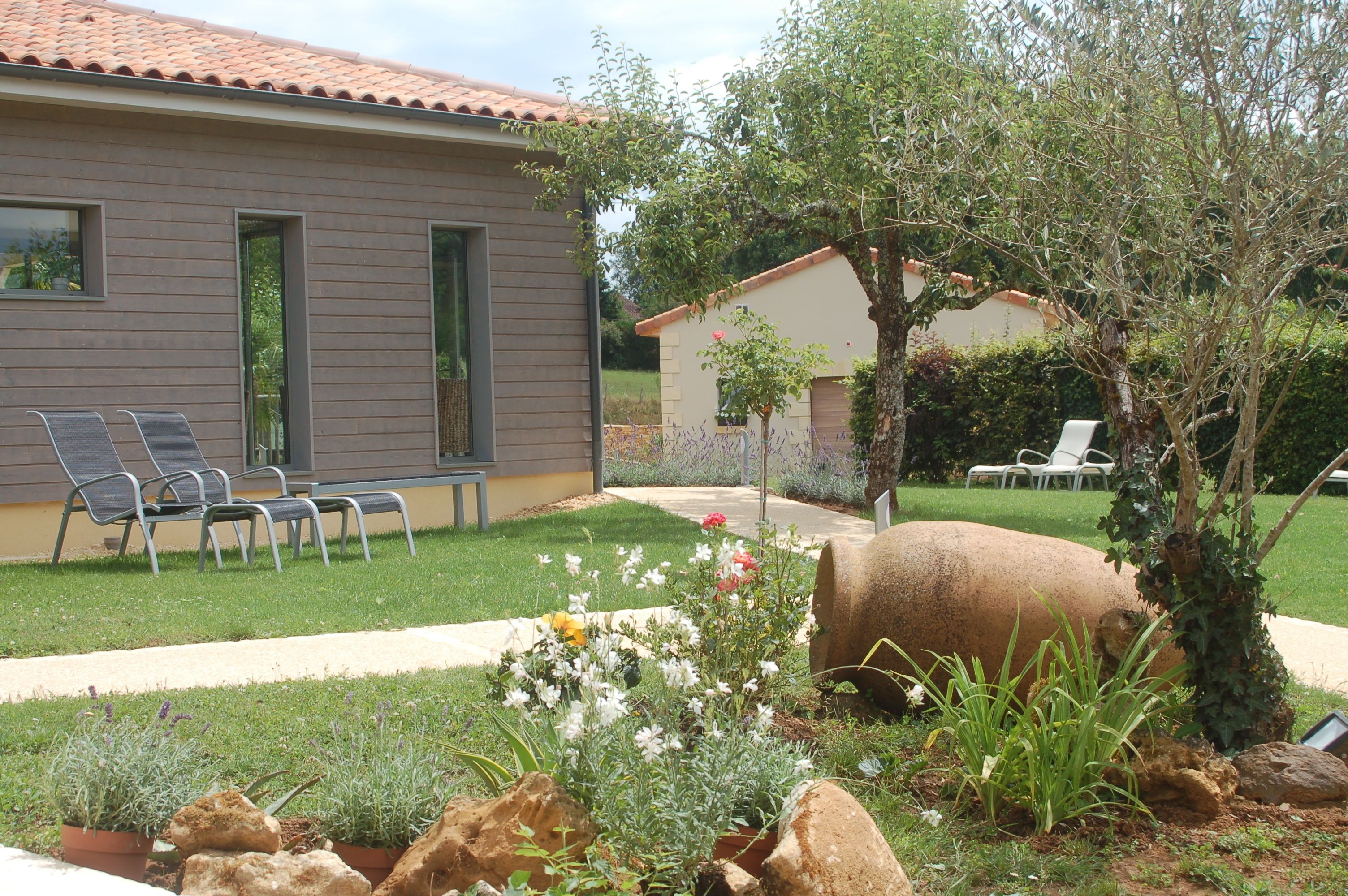 A modern house with a patio area featuring outdoor seating and a well-maintained garden with rocks and plants.