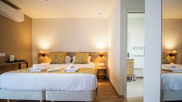 A hotel room with two beds, a wooden headboard, bedside lamps, a small table, and a mirror.