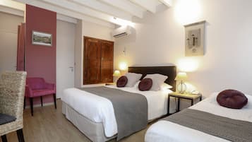 Una camera d'albergo con due letti, un armadio in legno, una sedia e un comodino con una lampada.
