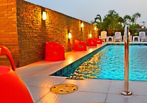 A poolside area with a brick wall, red chairs, and a pool.
