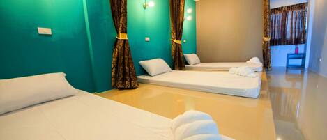 Habitación de hotel con dos camas individuales, paredes color aguamarina y un espejo grande.