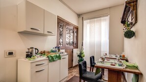 Une cuisine compacte avec un coin repas, comprenant un meuble en bois, une machine à café et une table à manger pour deux personnes.