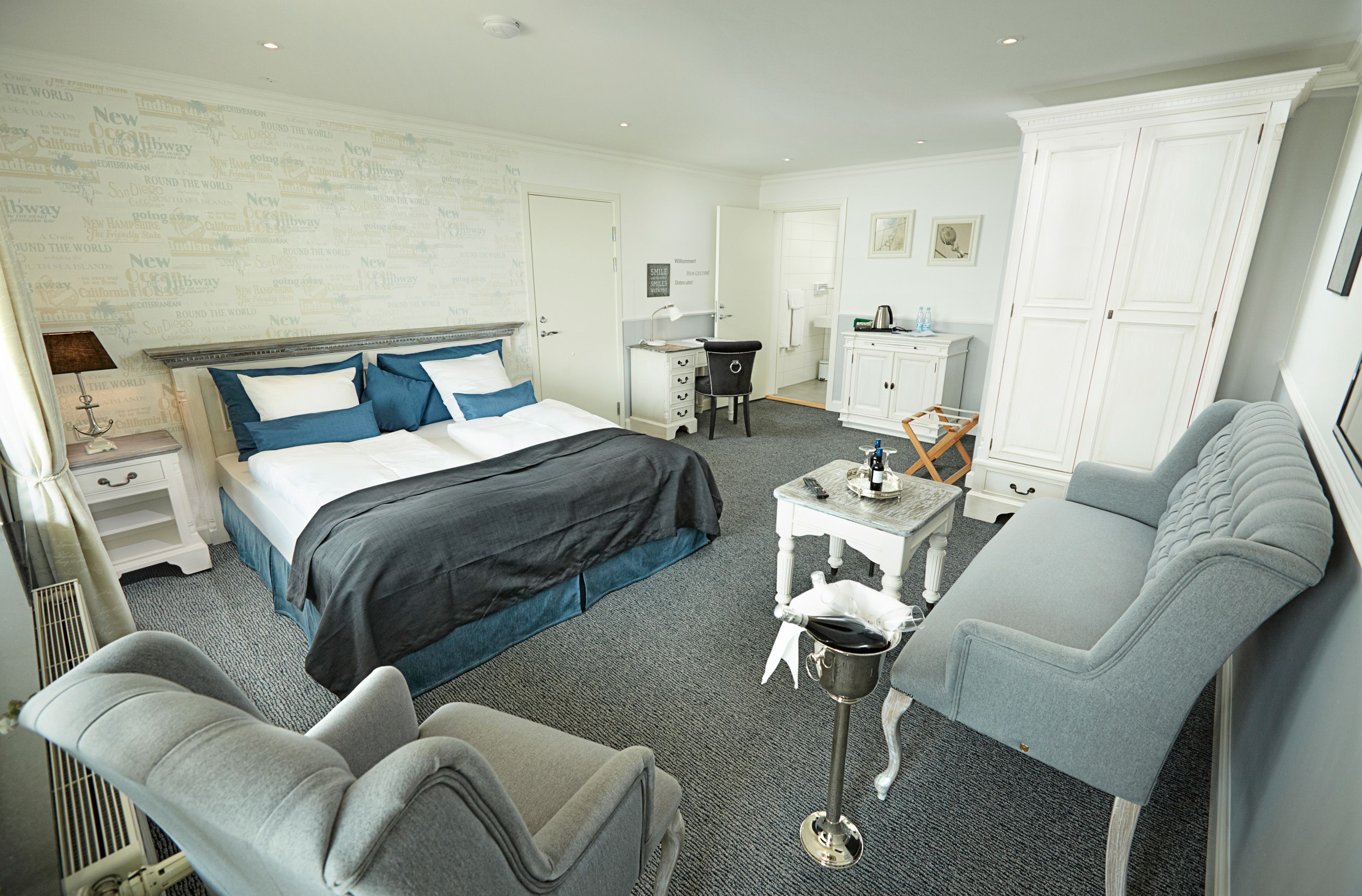 A hotel room with a bed, a desk, a chair, and a wardrobe.